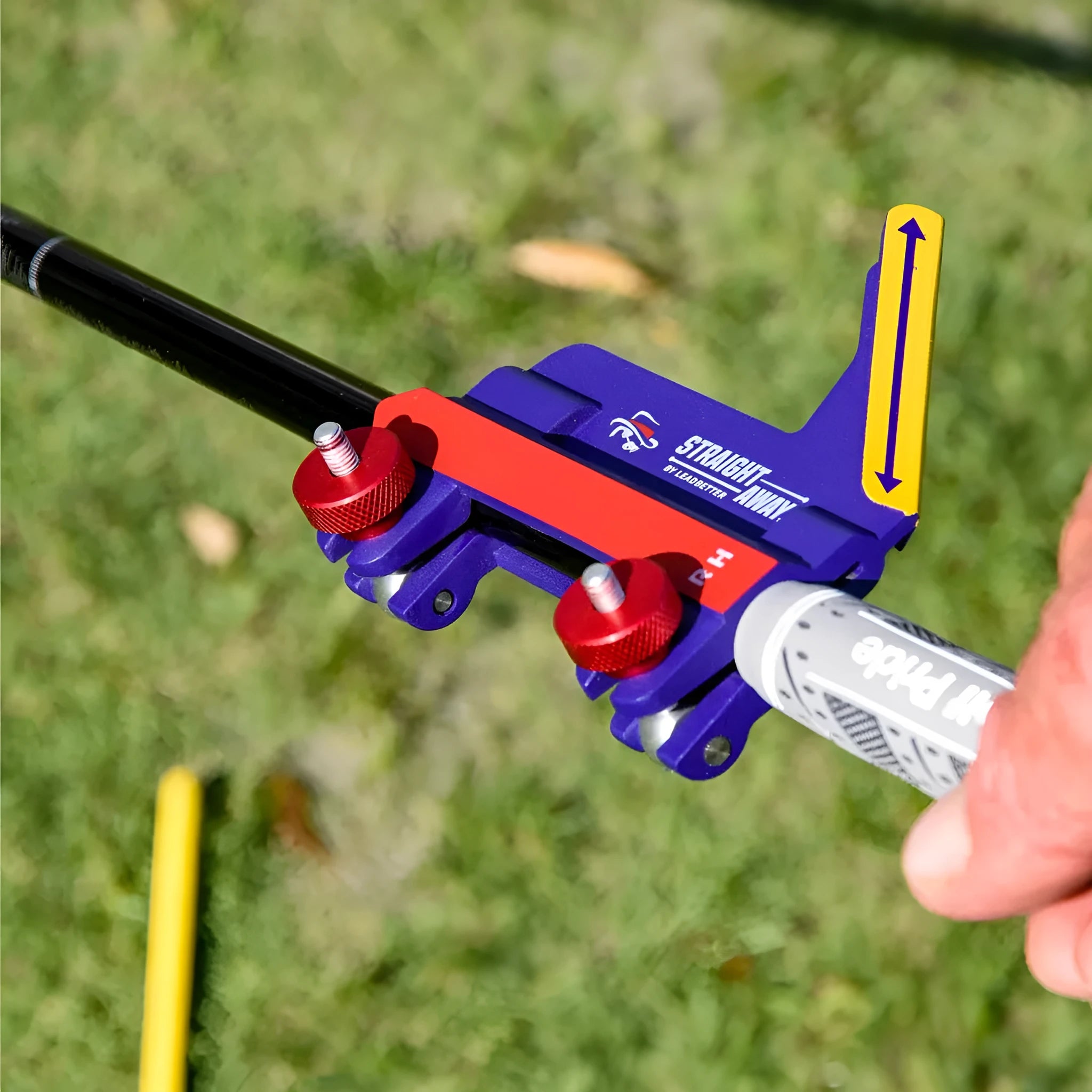 A plastic golf swing plane simulator training aid on a green background.