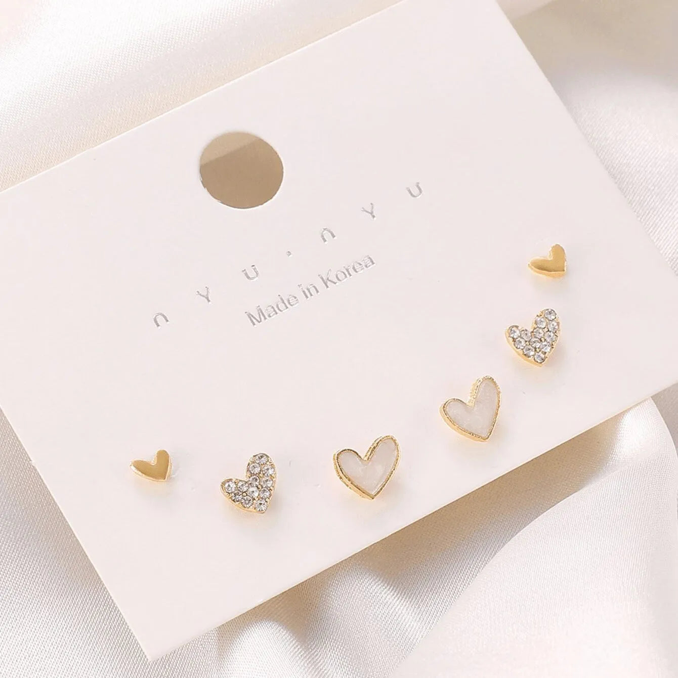 Three pairs of women's heart-shaped alloy earrings in gold, black, black-white, and pink colours