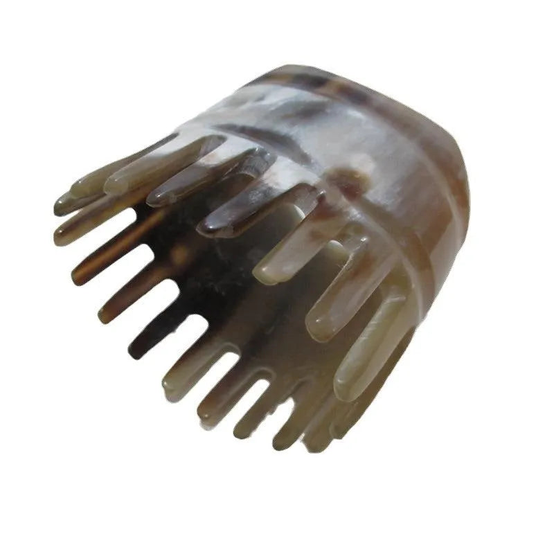 A white buffalo horn comb with wide teeth and a pointed tip for scalp massage.