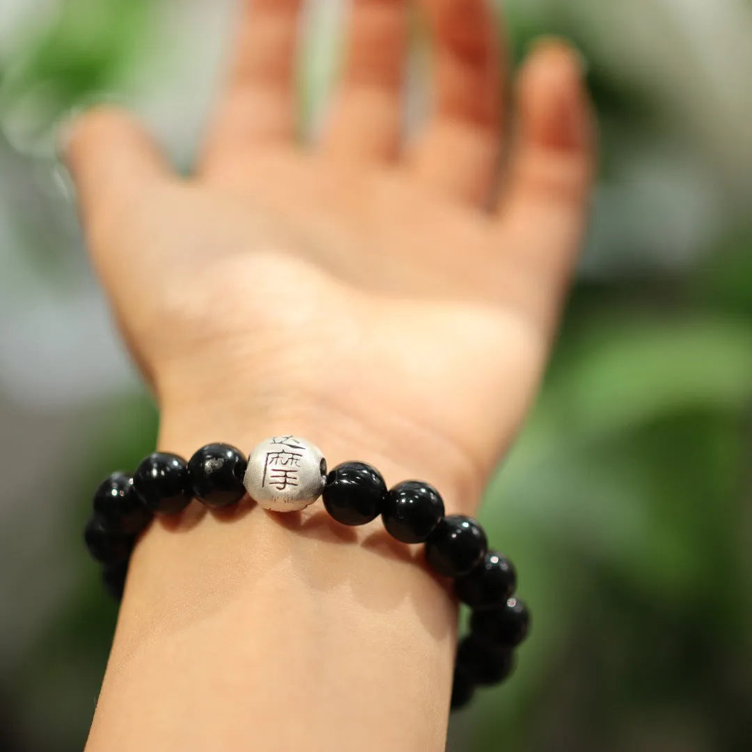 Close-up of a women's black agate bead bracelet with a sterling silver clasp on a wrist.