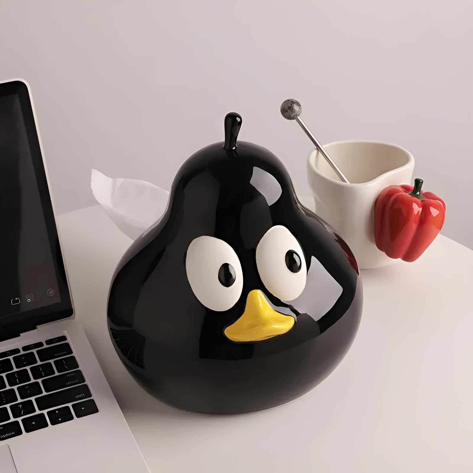 A cute pear-shaped white ceramic tissue box holder with an animal design, shown in green and black colour options.