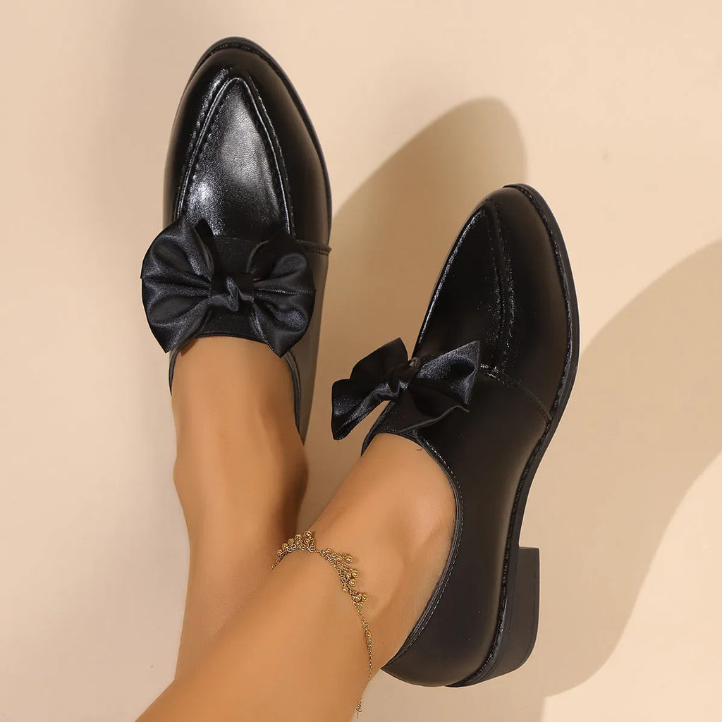 Women's brown leather-look shoes with a decorative bow detail on a flat rubber sole