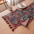 Dark blue striped Nordic jacquard bouquet table runner with tassel trim laid flat on a table.