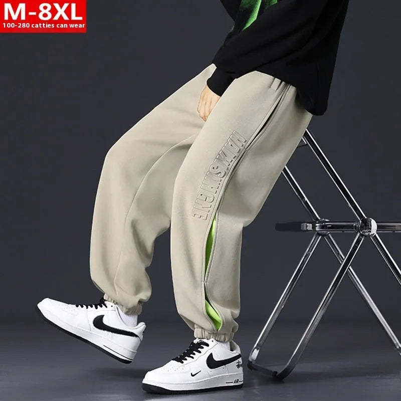 Man wearing loose grey-green trousers with stitching print detail and ankle banding.