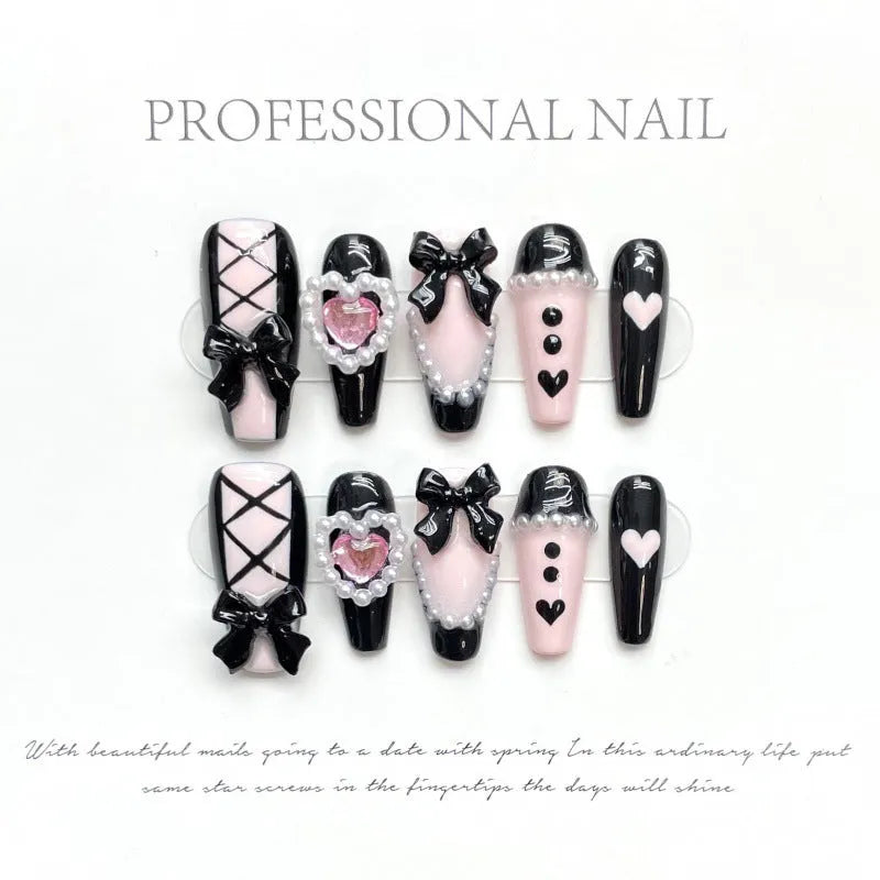 Black and pink heart hand-painted artificial nails with bow detailing in mid-length cat's eye design