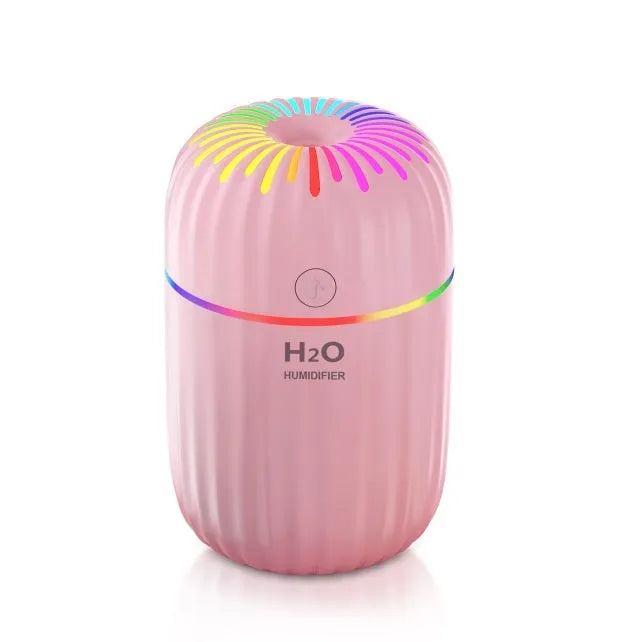 Small white Fireworks USB desktop humidifier with water tank on a wooden desk.