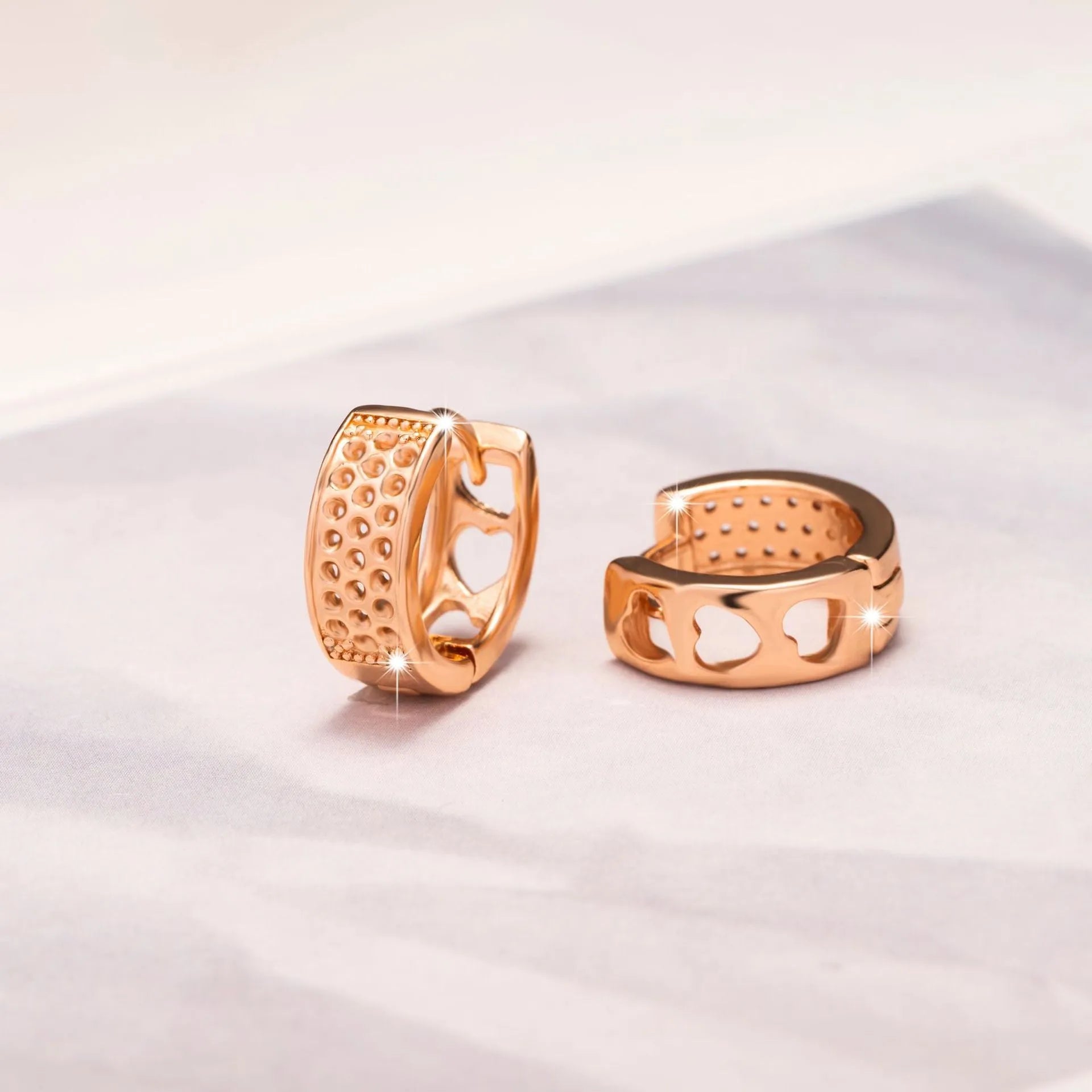 Rose gold women's earrings with three hollowed-out hearts in circular drop design