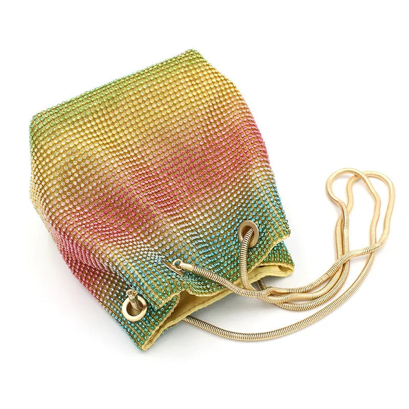 Soft rainbow-coloured rhinestone bucket bag with a silver chain shoulder strap on a white background.