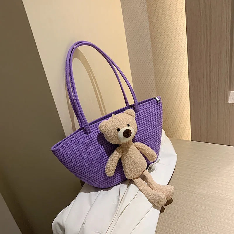 Large beige woven cotton linen shoulder bag with three-dimensional front pocket and double straps.