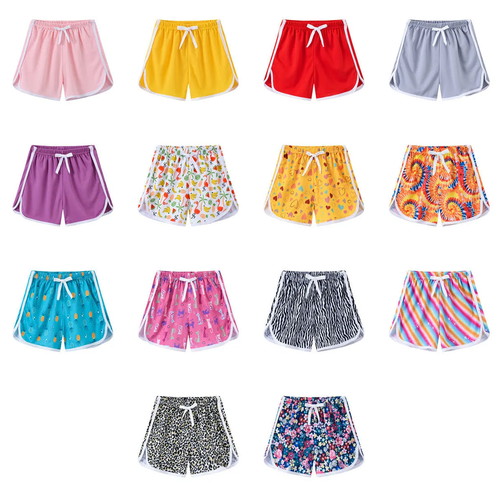Children's patterned beach shorts in various colours including leopard print, floral, and fruit designs