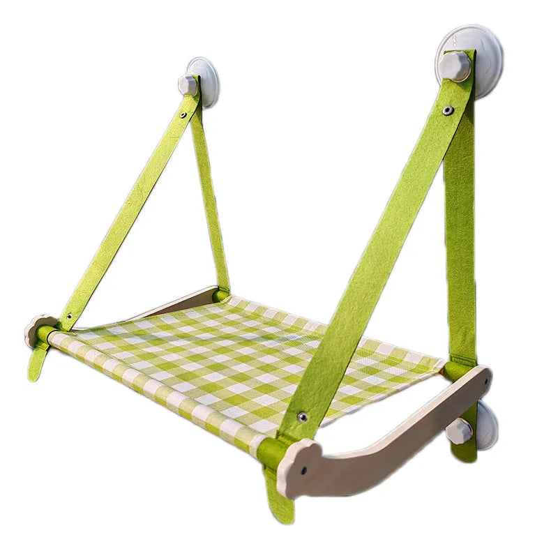 Wooden frame cat hammock with linen cushion mounted on a window, shown in green colour.
