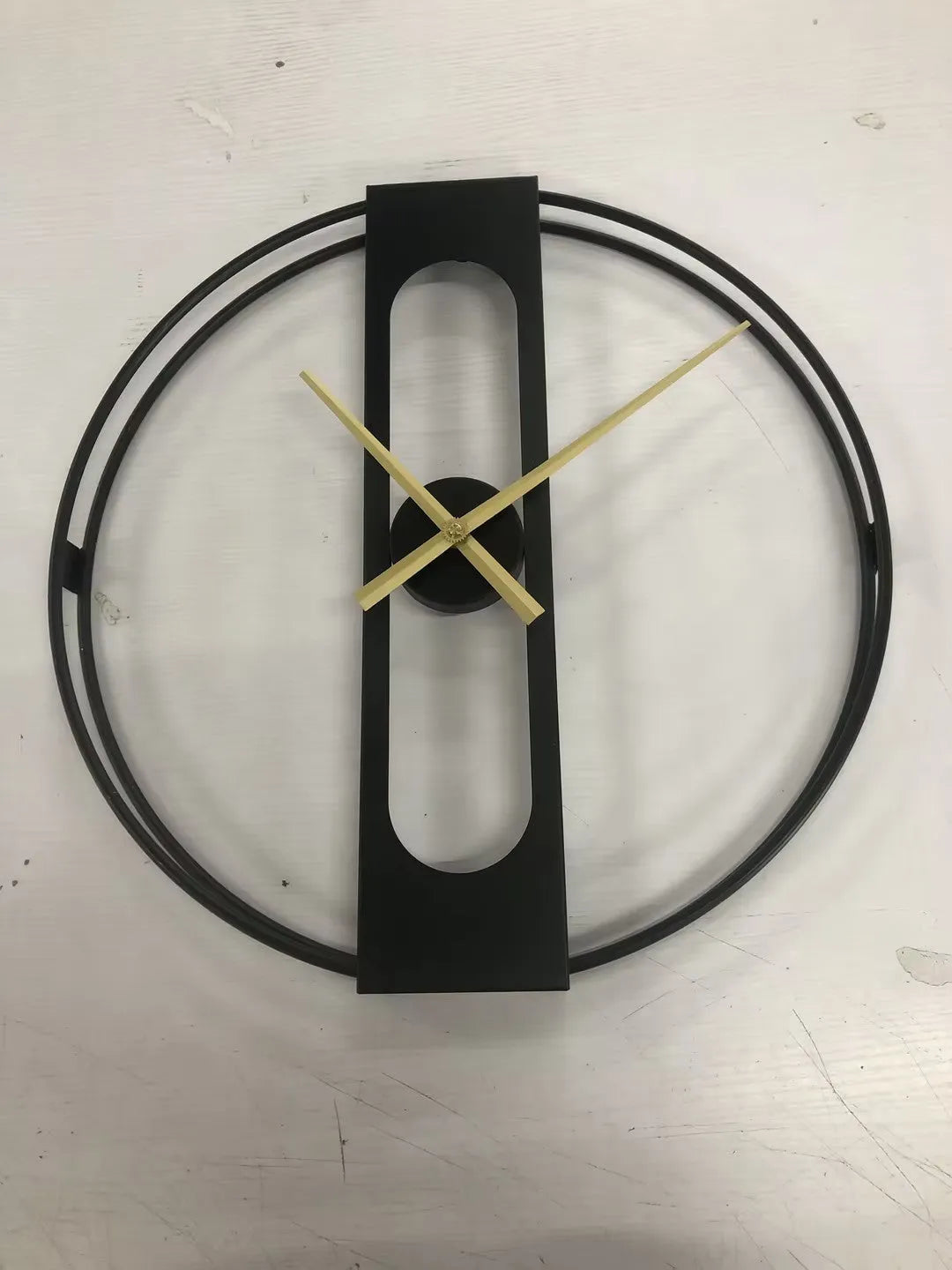 A large 50cm round metal wall clock on a wall, shown in black and gold colour variants.