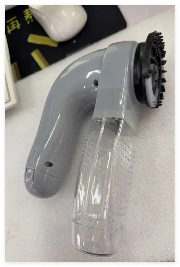 Grey portable pet hair vacuum cleaner with soft rubber head and large collection canister on a fabric sofa.