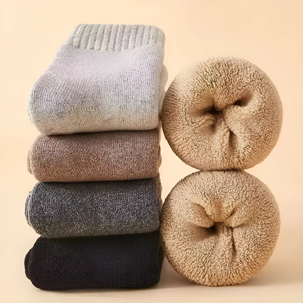 Two pairs of thick grey winter wool socks with a merino midsole next to a storage box