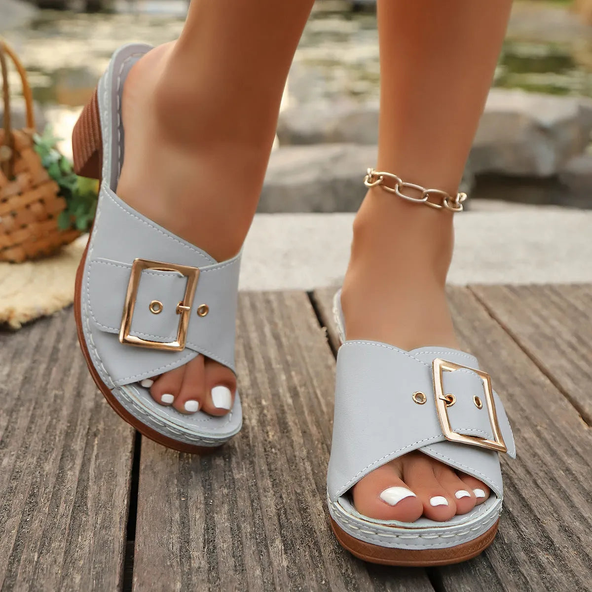 Women's black chunky heel slippers with a round toe and metal buckle on a light background.