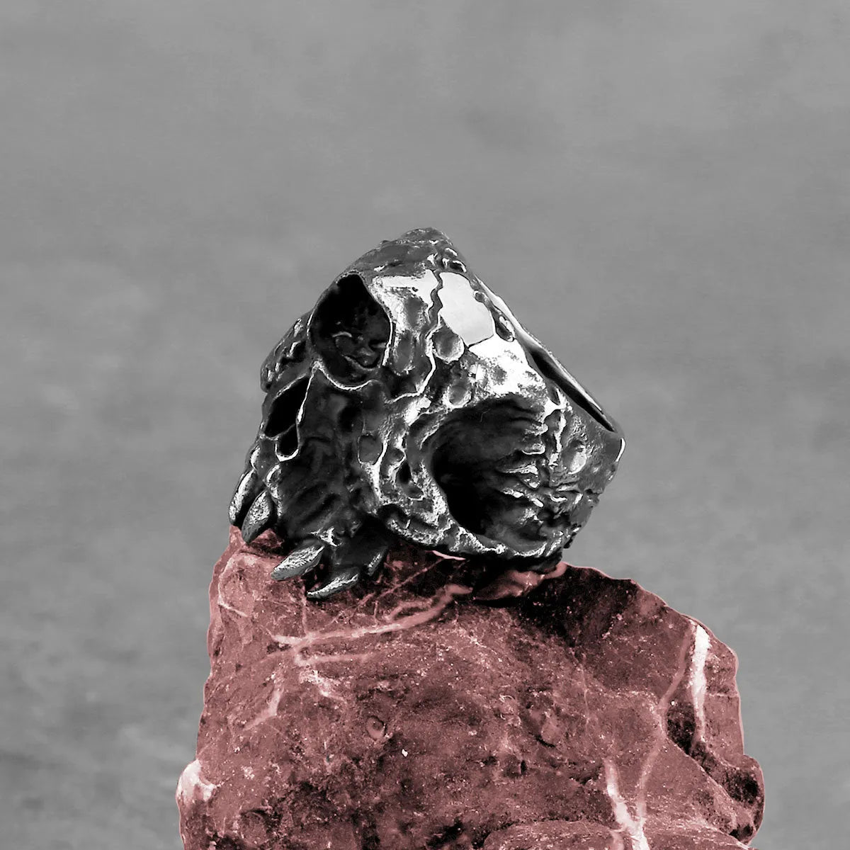 A close-up view of a silver-toned alloy ring featuring a detailed one-eyed skull design in a retro punk style.