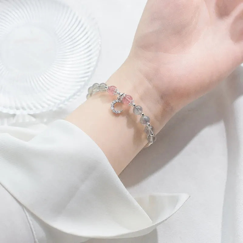Handmade adjustable moonstone bracelet with crescent moon charm and crystal bead on wrist.