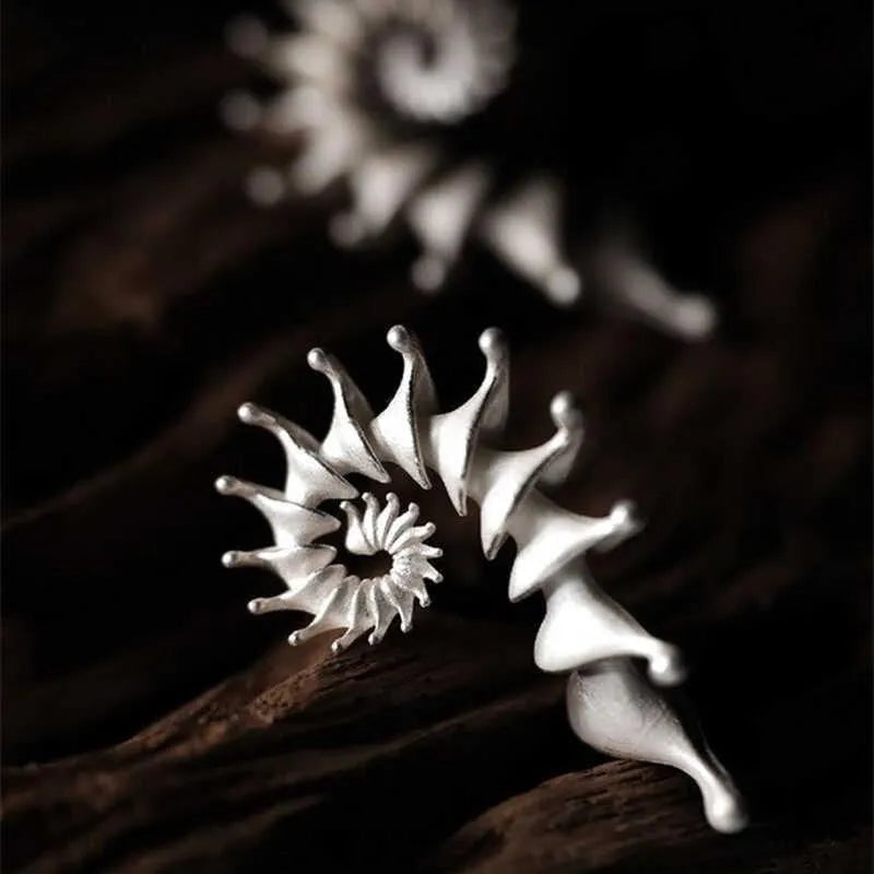 A pair of matte conch-coloured alloy stud earrings with an exaggerated three-dimensional shape.
