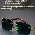Dark green frameless crystal sunglasses on a case with a lens cloth.