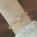 Yellow gold electroplated copper bracelet with a geometric bells of Ireland butterfly and Hetian jade design for women.