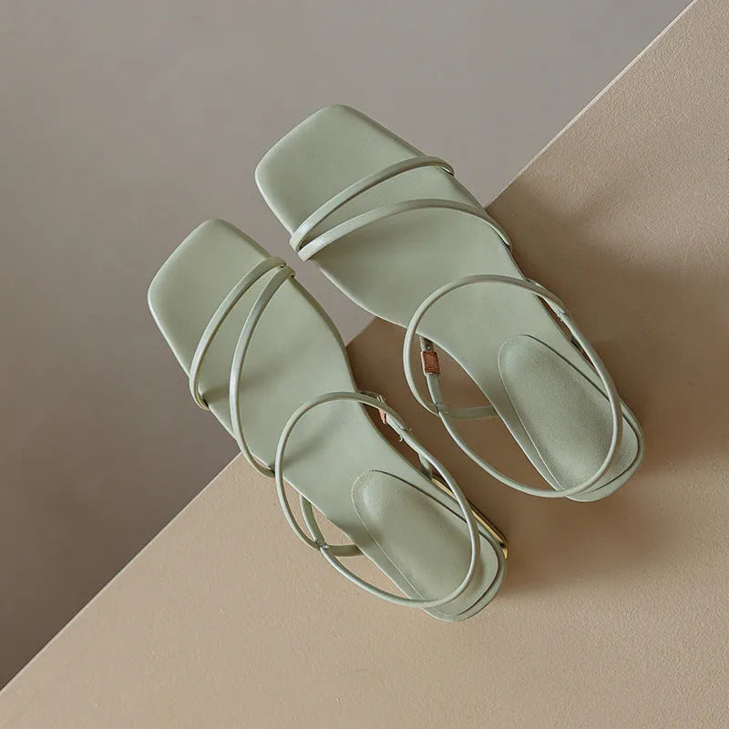 Women's beige flat strap Roman sandals with an open toe and square toe bracket on a white background.