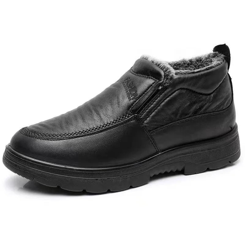 Men's black fleece-lined winter slip-on shoes with rubber sole on a wooden floor.