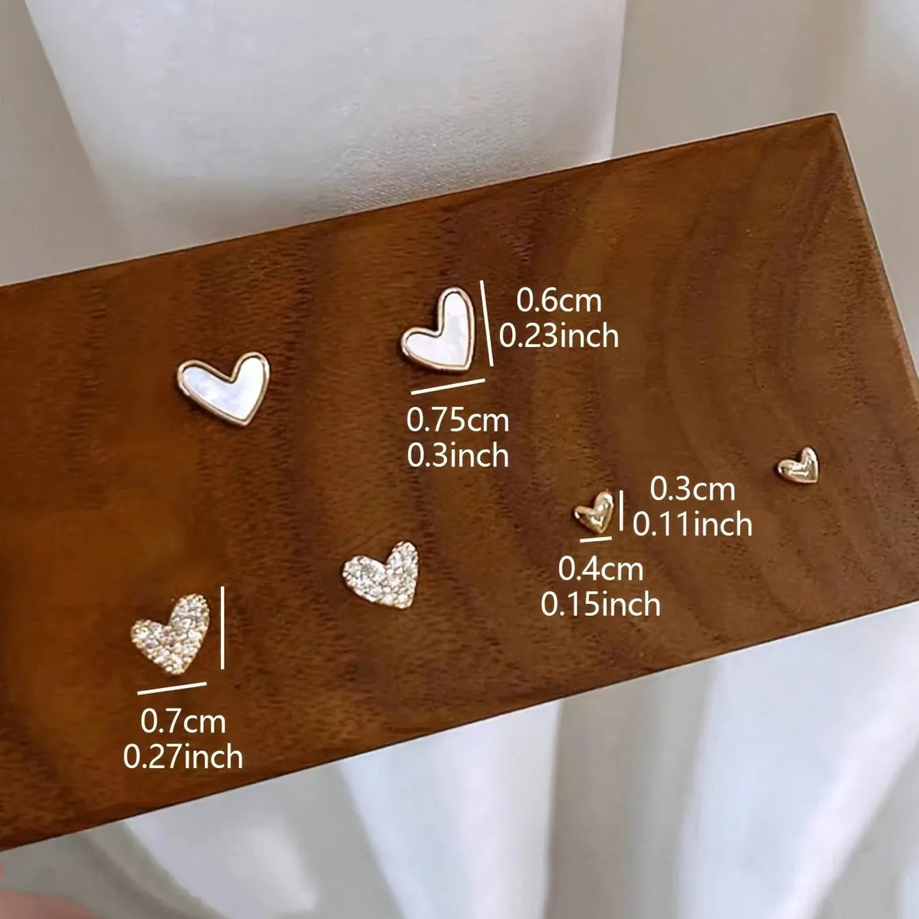 Three pairs of women's heart-shaped alloy earrings in gold, black, black-white, and pink colours