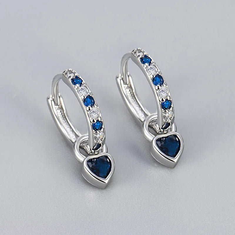 Women's fashion earrings with heart-shaped drops containing coloured gemstones in gold or white gold colour settings