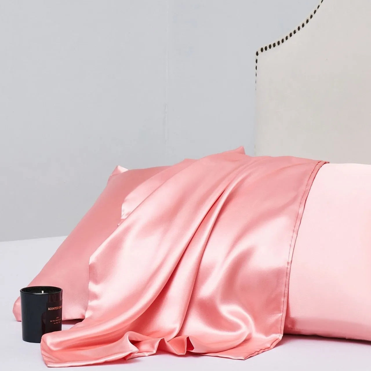 A pair of solid colour satin pillowcases in various colours and sizes on a bed.