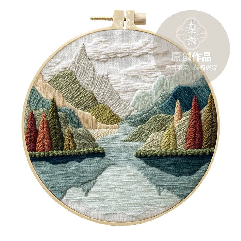 Embroidery kit with printed landscape fabric, thread, bamboo frame, and needles arranged for DIY cloth art