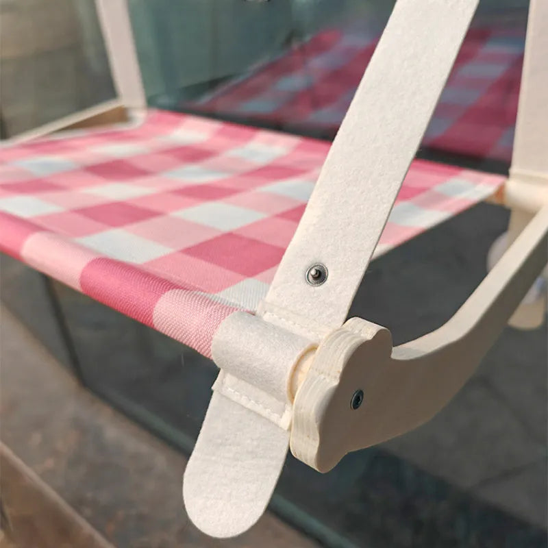 Wooden frame cat hammock with linen cushion mounted on a window, shown in green colour.