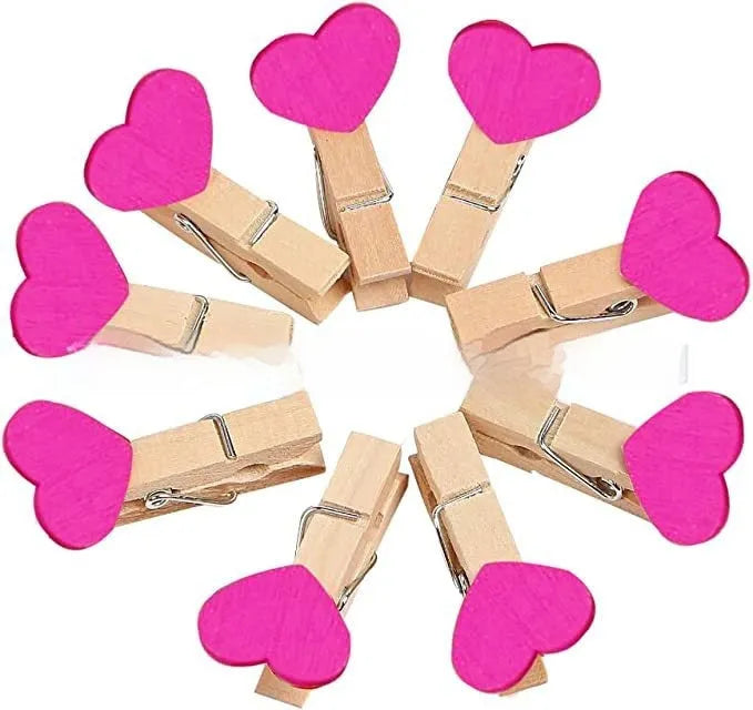Five small handmade solid wood heart-shaped clips in assorted colours on a white surface.
