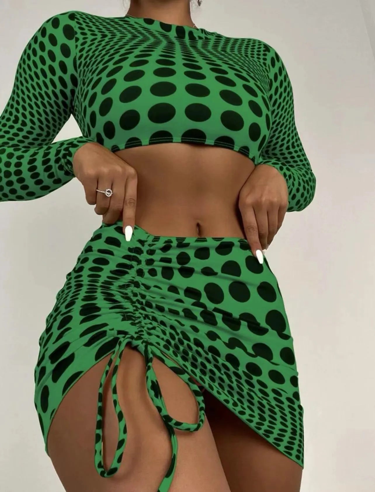 Women's green polka dot three-piece swimsuit set with bra top and skirt on hanger