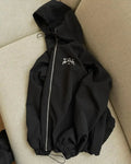 A grey men's hooded loose-fit sunscreen jacket on a hanger, showcasing its British-style design.