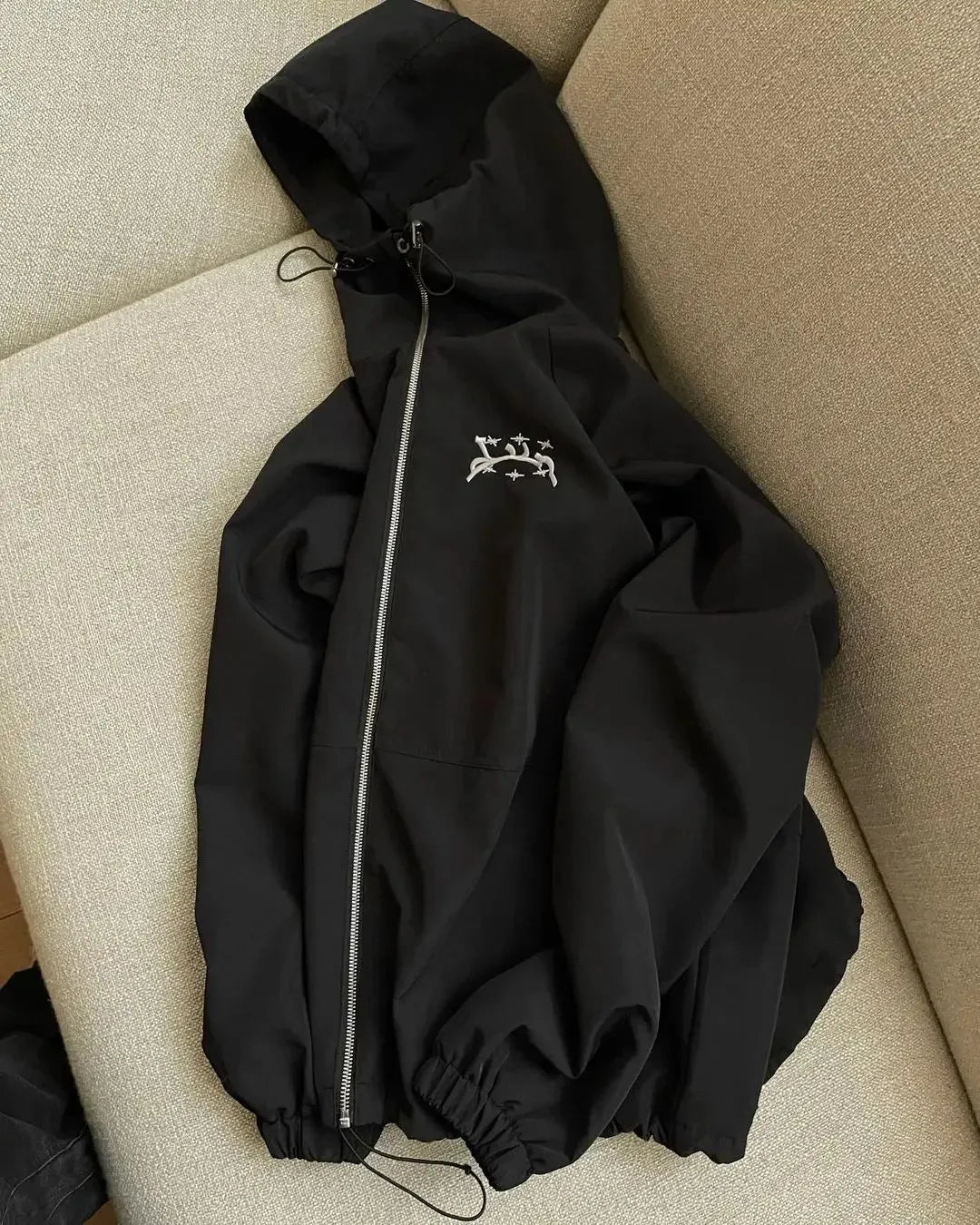 A grey men's hooded loose-fit sunscreen jacket on a hanger, showcasing its British-style design.