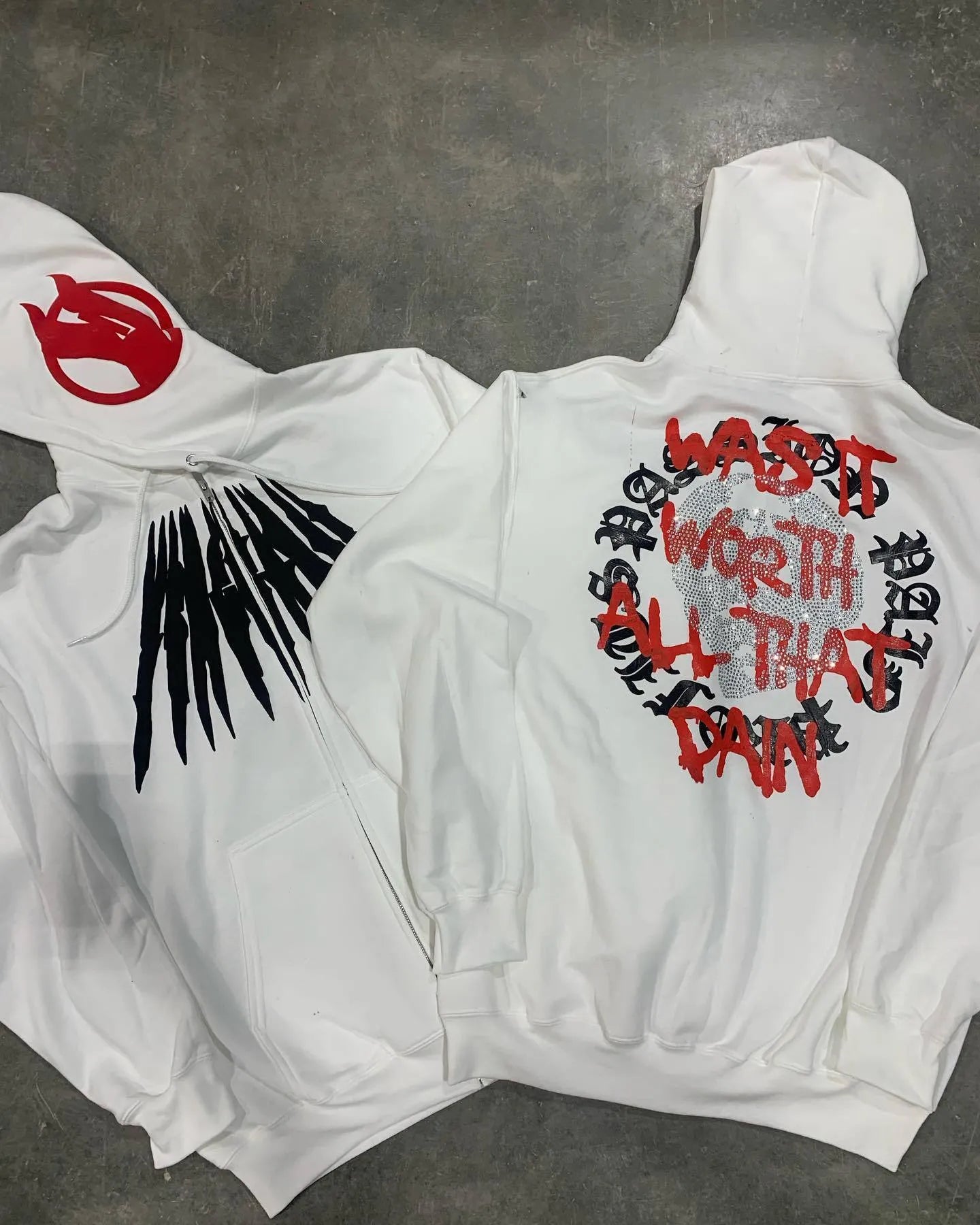 Black hooded sweatshirt cardigan with a white printed skull and rhinestone design on the front.