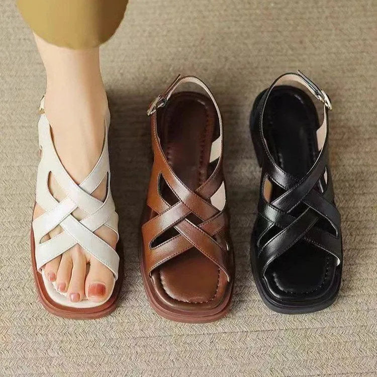 Women's black patent leather square toe sandals with cross straps on a low rubber sole.