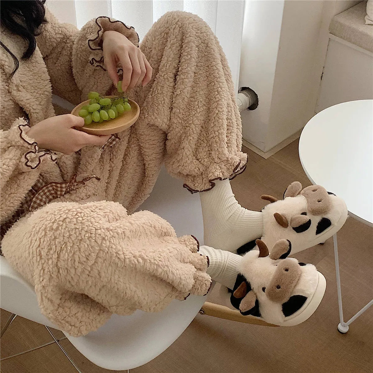 White cow plush slippers with non-slip textured soles shown from above
