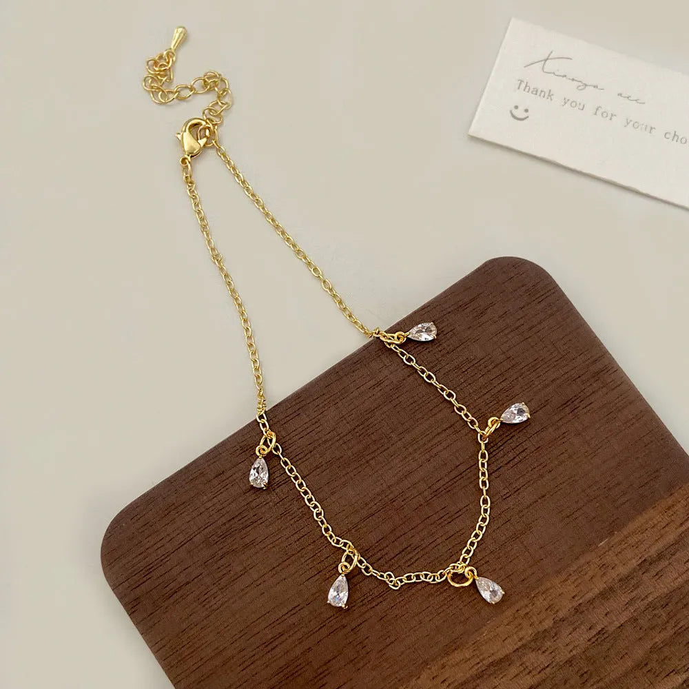 Women's zircon jewellery set with geometric meteor shower necklace, matching earrings, and anklet.