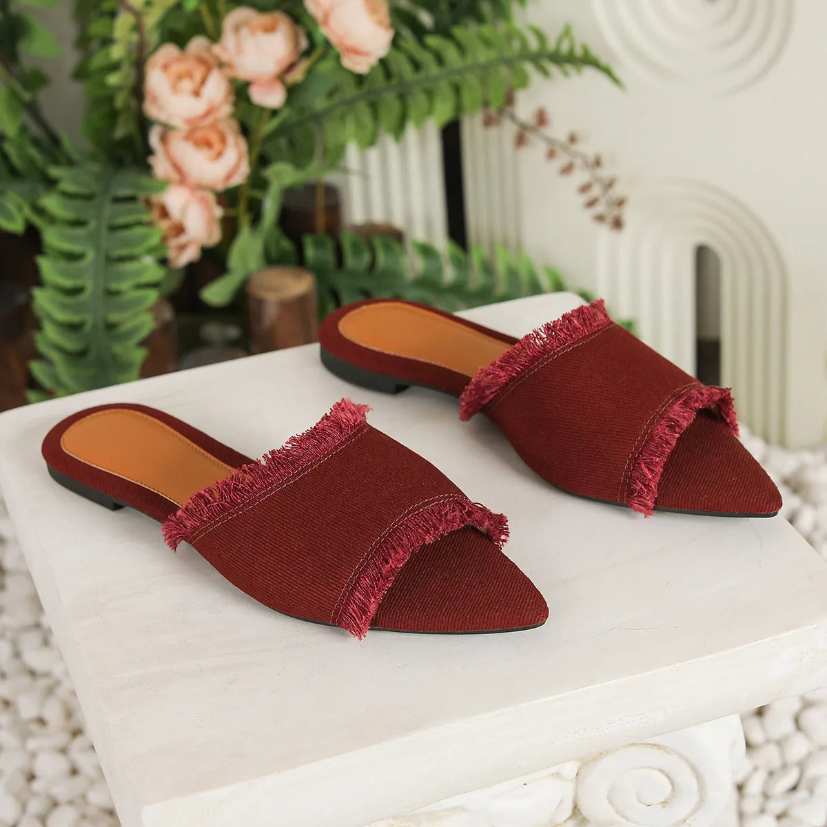 Women's denim flat slippers with tassel detail and leather lining in various colours.