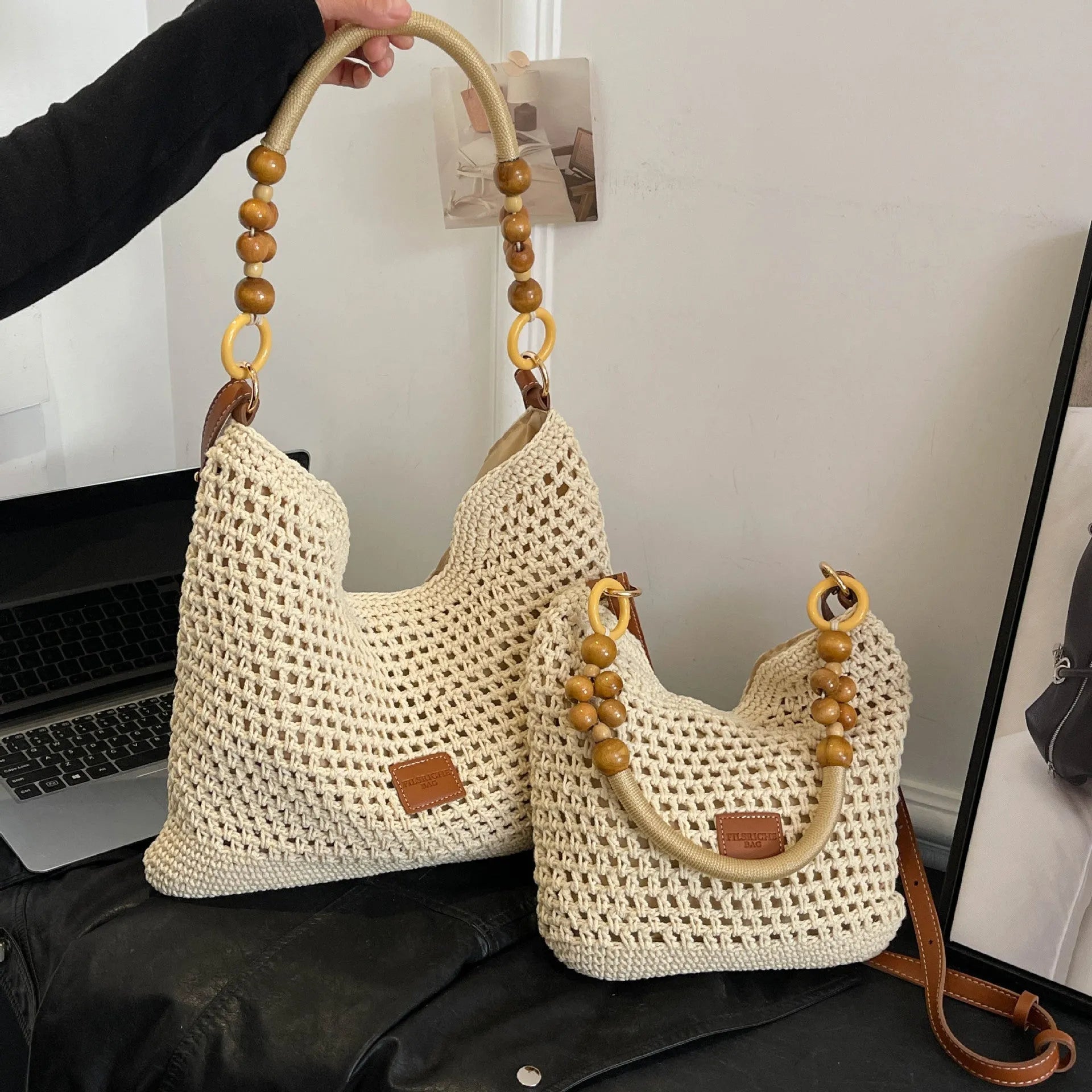 Knitted bucket-shaped tote beach bag with crossbody strap, shown in black, featuring contrasting stitching.