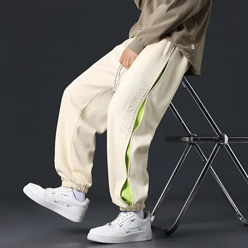 Man wearing loose grey-green trousers with stitching print detail and ankle banding.