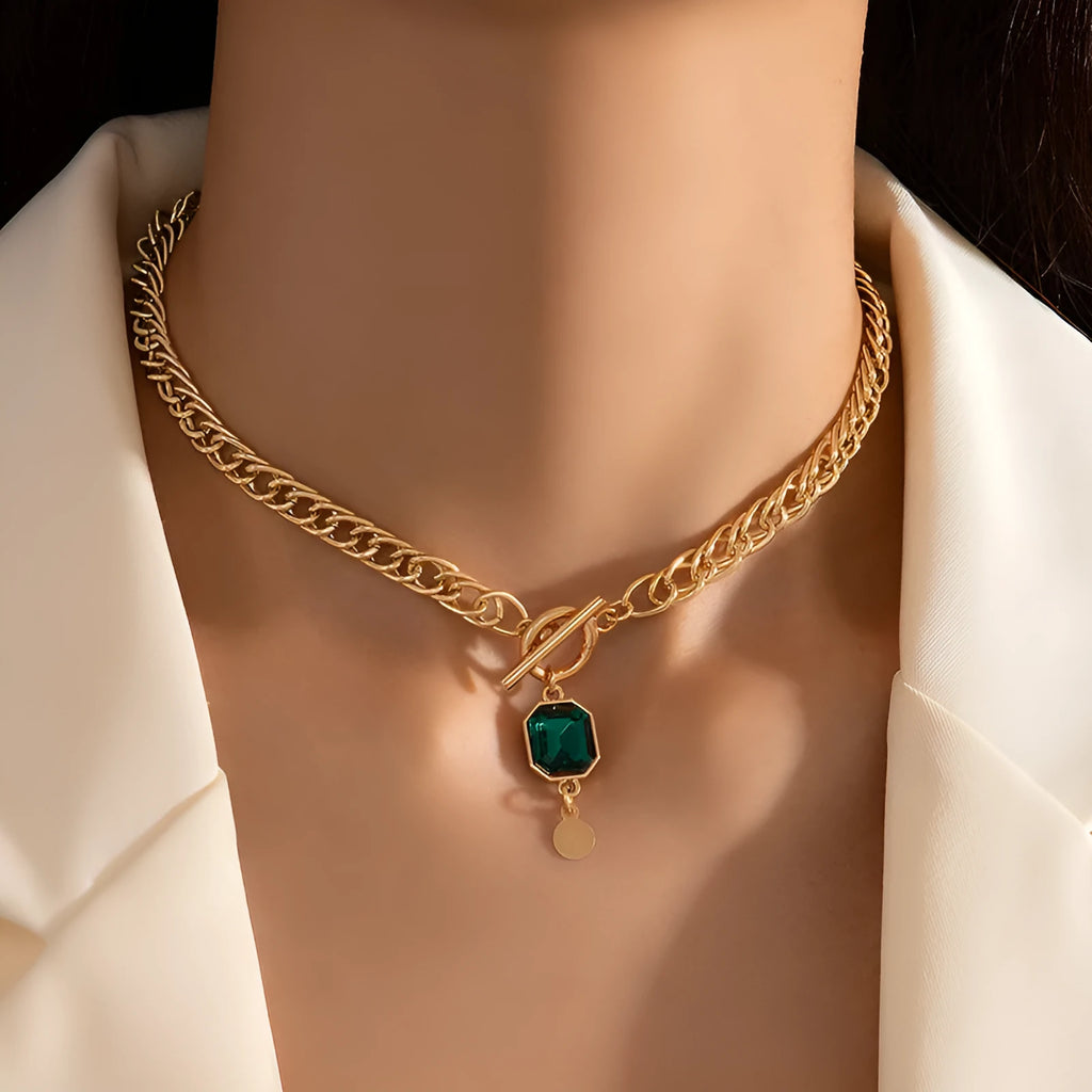 Gold electroplated titanium steel pendant necklace with geometric design and emerald zircon accents on Cuban link chain