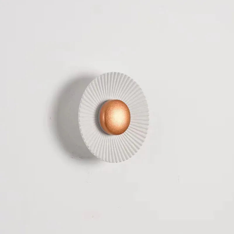 Round aluminium wall lamp with outer white and inner gold finish mounted on a wall