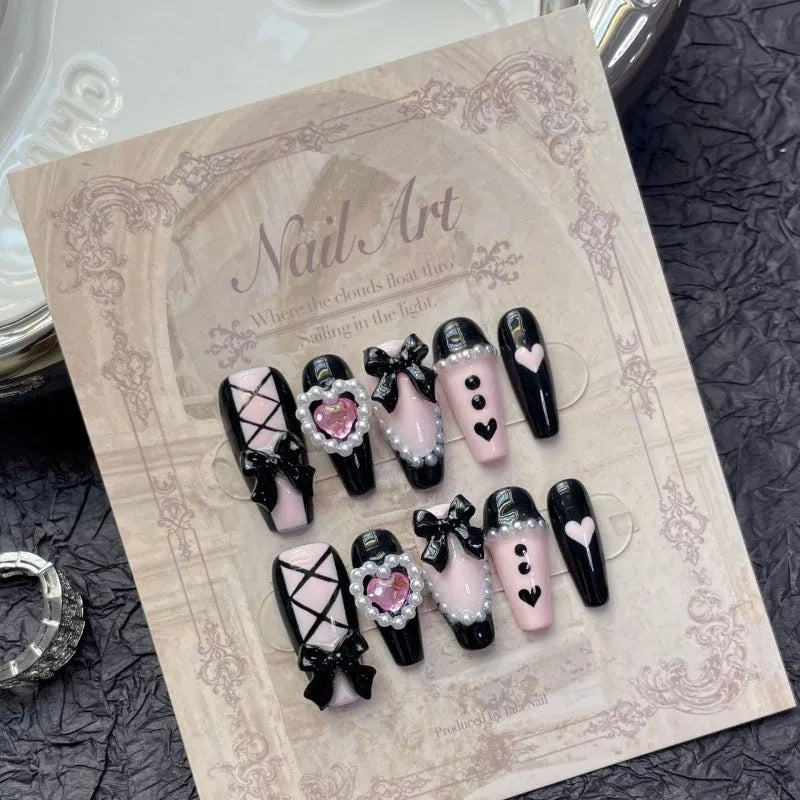 Black and pink heart hand-painted artificial nails with bow detailing in mid-length cat's eye design